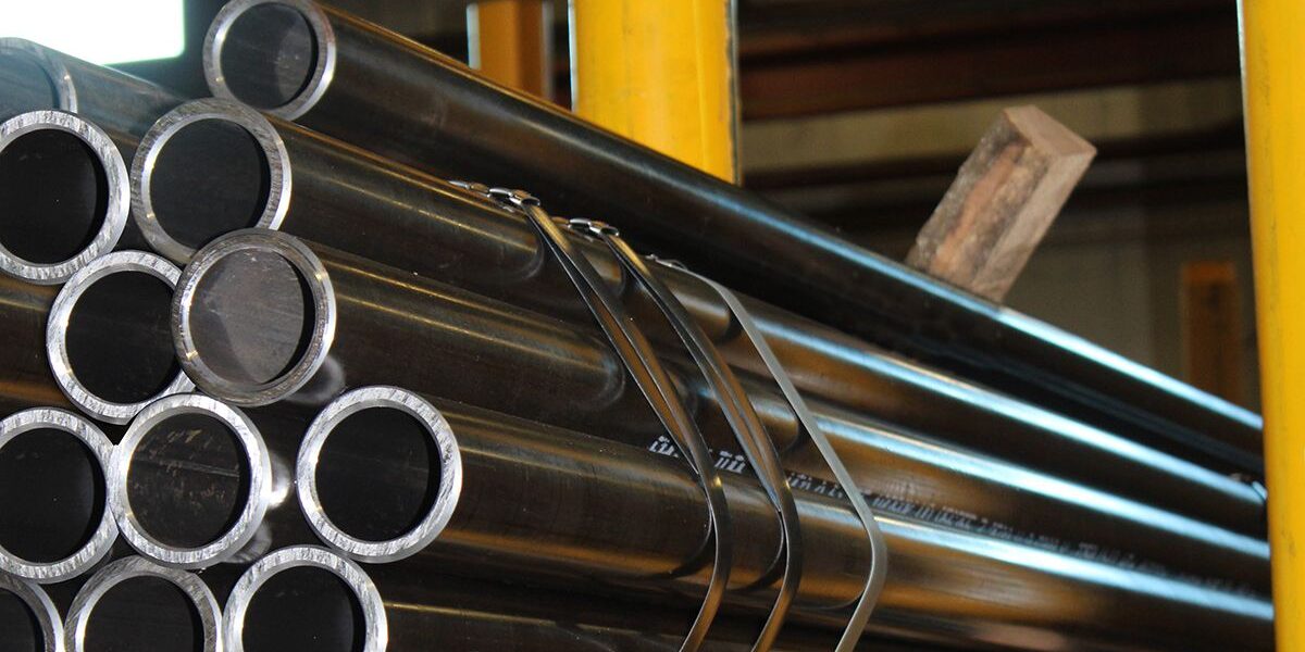 1732027289530 Marmon Keystone A stack of metal tubes is shown in a warehouse setting with the text “Marmon/Keystone Tube Pipe Bar IN STOCK,” highlighting our role as a leading supplychain distributor in metals.