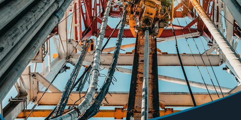post-1-4 Marmon Keystone View looking up at steel pipes and equipment on an oil drilling rig, with text promoting Marmon/Keystone as your trusted metals distributor—with DOM tube and pipe in stock and ready to ship for oilfield supply chain needs.