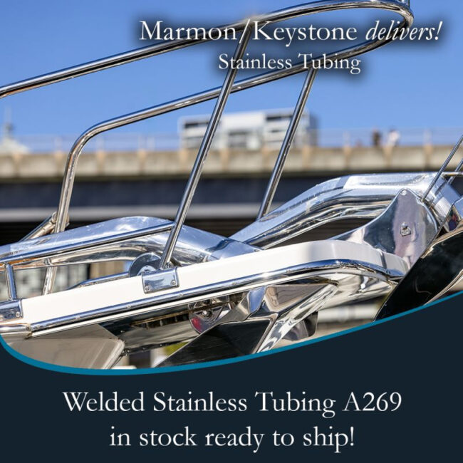 post-1-8 Marmon Keystone Close-up of polished stainless steel tubing on a boat railing with promotional text for Marmon/Keystone welded stainless tube and pipe, A269. In-stock metals, ready to ship from your trusted supply chain distributor. Bridge and sky in the background.